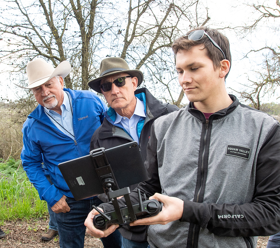 From left, California Water Commissioner Joe Del Bosque and California Water Commission Chair Armando Quintero watch live video feed from a drone operated by University of California, Merced Researcher Michael Kalua, Jr. at the Oneto-Denier Floodplain Restoration Project in the Cosumnes River Watershed near Galt.