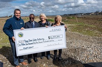 California Natural Resources Agency Secretary Wade Crowfoot, left, Steve Doe, Special Investigations Branch Manager, DWR, Mary Fast – Kings Water Authority Board Chair, and Alma Beltran, Mayor of Parlier, are seen at this event posing with this check presented to them by DWR in front of other local officials from across the Central Valley, in Parlier, at the Foothill Basin Project Site, some of which is seen behind the fence in the background, before $15 million in financial assistance from DWR’s Integrated Regional Water Management (IRWM) Program was presented.